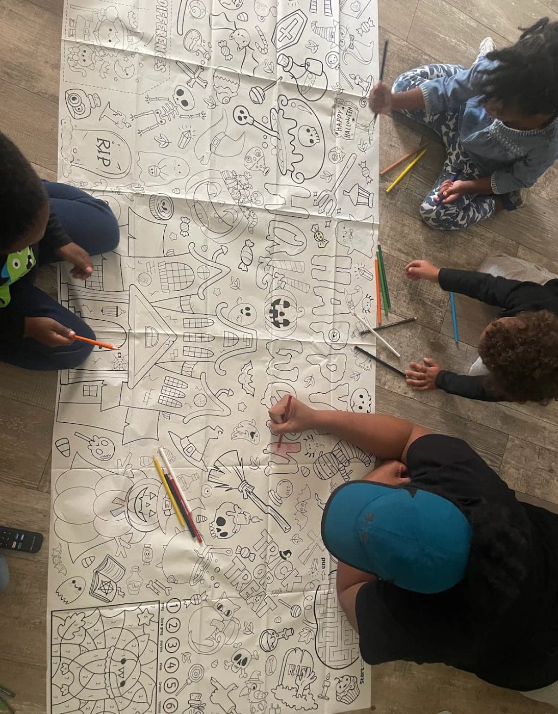 Kids coloring a giant Halloween poster together on the floor